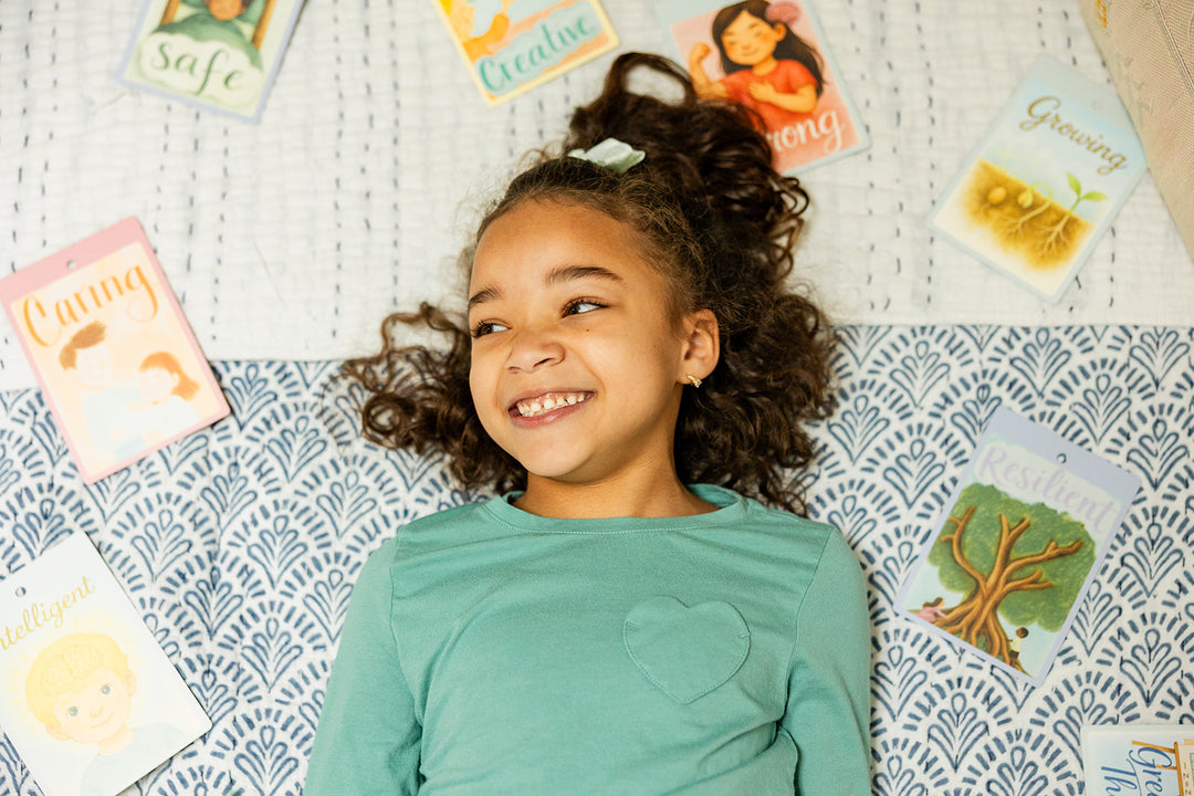 Child looking into a mirror on an affirmation chart with word cards
